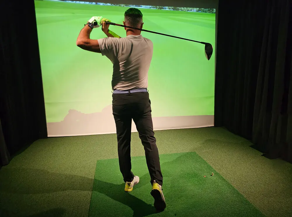 Golfer swinging in indoor simulator